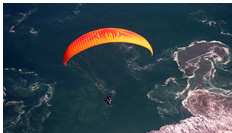 Tandem paraglider flying into the sea over Playa Brava, Iquique, Chile